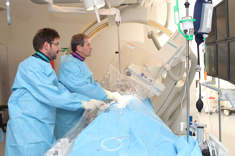 Zwei Ärzte behandeln einen Patienten im Herzkatheterlabor; verlinkt zur Seite 'Herzkatheterlabor'