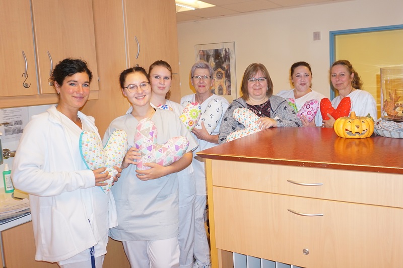Gruppenfoto zum Herzkissenprojekt: sieben Frauen, die jede ein Herzkissen aus unterschiedlichen Stoffen halten