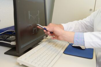 zwei Hände zeigen auf einen Laptopmonitor mit Röntgenbild eines Schädels zwei Hände zeigen auf einen Laptopmonitor mit Röntgenbild eines Schädels