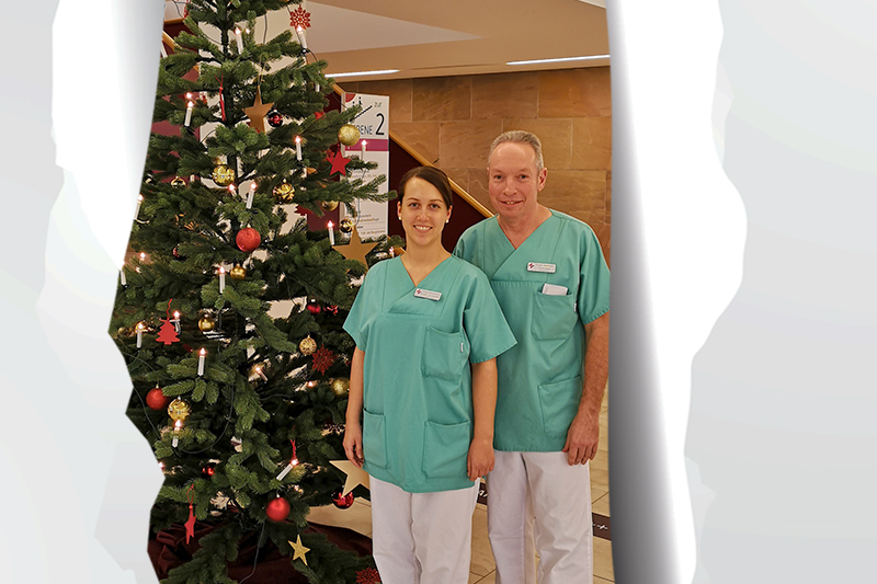 Tag 17: Fenja Buschhardt und Frank Heimrath vor dem weihnachtlich geschmückten Tannenbaum am KBR