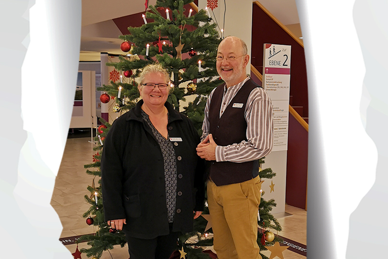 Tag 9: Claudia Huter-Dosdal und Martin von der Brelje vor dem weihnachtlich geschmückten Tannenbaum am KBR