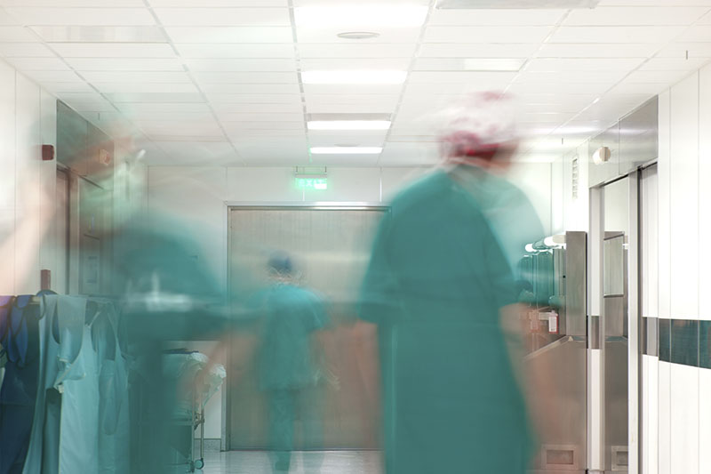 Personal in grüner OP-Kleidung in Bewegung vor den Operationsräumen; verlinkt zur 'Klinik für Unfall- und Handchirurgie, Orthopädie'