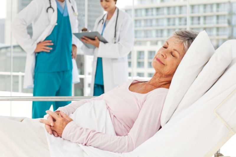 Schmuckbild: eine lächelnde Seniorin im Krankenhausbett, im Hintergrund zwei Ärzte (Quelle: iStockphoto.com)