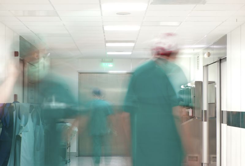 Personen in grüner OP-Bekleidung in Bewegung vor den Operationsräumen; verlinkt zur 'Sektion Gefäßchirurgie'