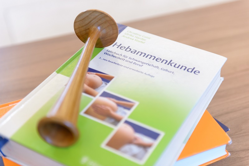 Schmuckbild: Lehrbücher der Hebammenkunde, darauf liegend ein hölzernes Hörrohr (Foto: Antje Schimanke) Schmuckbild: Lehrbücher der Hebammenkunde, darauf liegend ein hölzernes Hörrohr (Foto: Antje Schimanke)