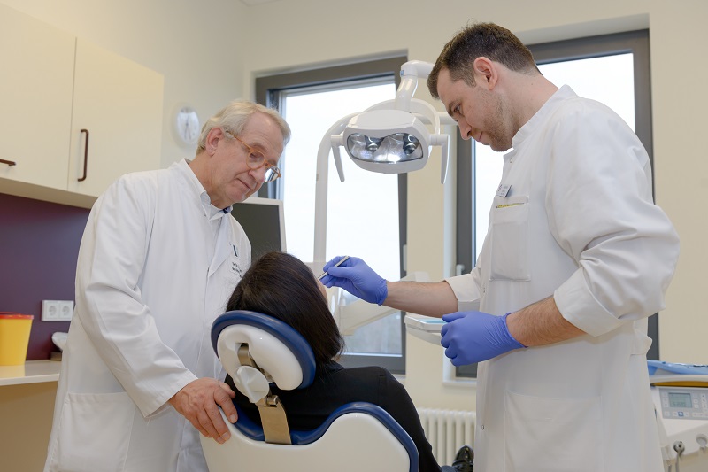 zwei Ärzte der Praxis für Mund-, Kiefer- und Gesichtschirurgie untersuchen eine Patientin; verlinkt zur Seite der Praxis