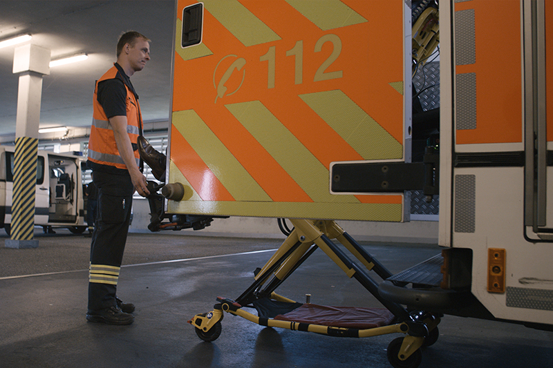 Eine Rollbahre mit einem Patienten wird von einem Mitarbeiter der Notfallmedizin aus dem Krankenwagen ausgeladen.