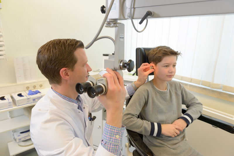 Ein Hals-Nasen-Ohrenarzt untersucht das Ohr eines Jungen; verlinkt zur 'Klinik der Hals-, Nasen-, Ohrenheilkunde'