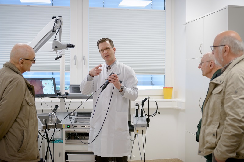 Szenenfoto vom Tag der offenen Tür in der HNO-Ambulanz: Dr. Ebmeyer erklärt Besuchern ein Untersuchungsgerät