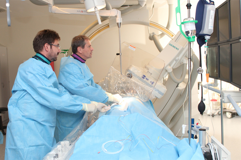 Zwei Ärzte behandeln einen Patienten im Herzkatheterlabor