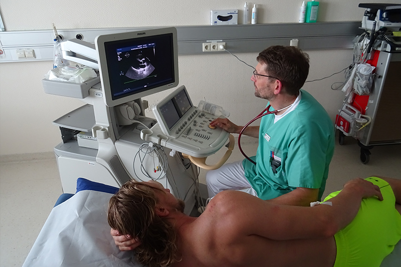 Szenenbild: Patient und Arzt während einer kardiologischen Untersuchung