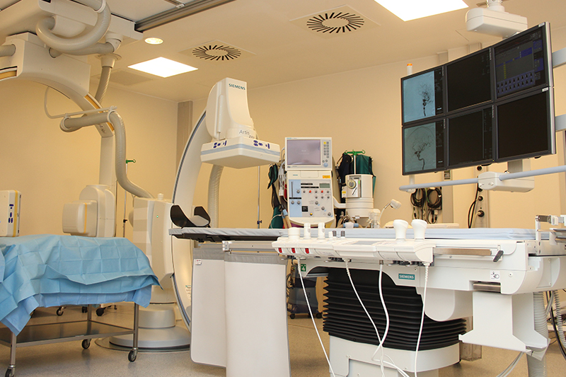 Untersuchungs- und Behandlungsliege mit Geräten und Monitoren im Herzkatheterlabor