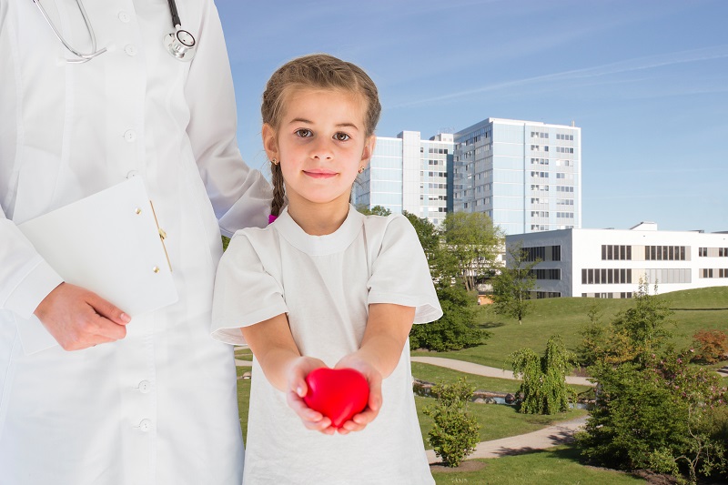 Schmuckbild: ein Kind steht neben einer Ärztin und hält ein rotes Herz in beiden Händen, im Hintergrund sieht man das Klinikum Bremerhaven-Reinkenheide