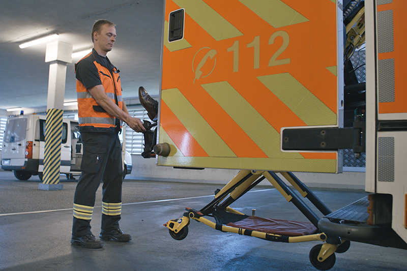 Ein Mitarbeiter des Rettungsdienstes lädt eine Bahre mit einem Patienten aus einem Rettungswagen aus