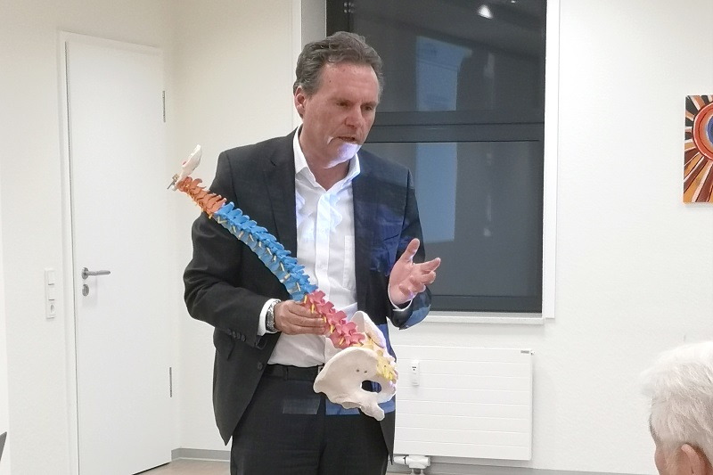 Professor Doktor Pinsker erklärt anhand eines Wirbelsäulenmodells