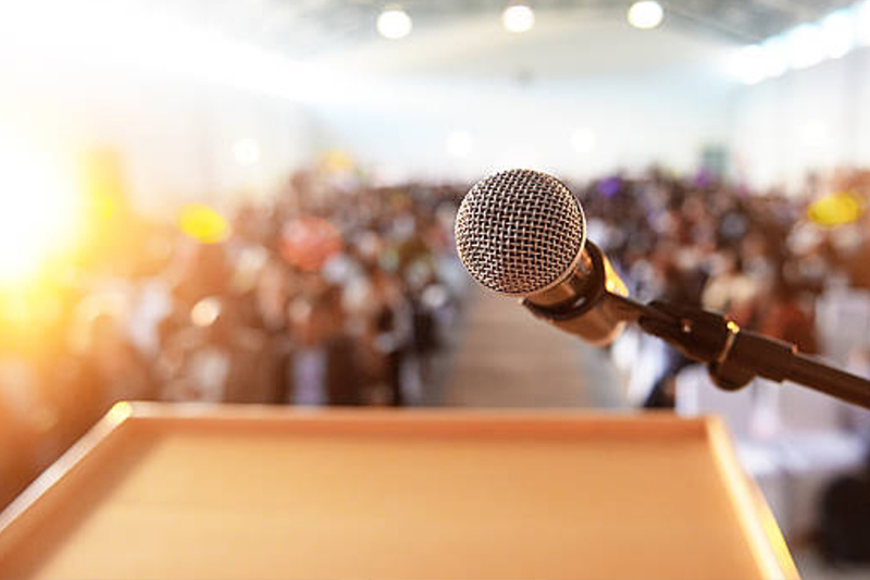 Schmuckbild: Blick von einem Rednerpult auf Mikrofon und Publikum; verlinkt zur Seite 'Veranstaltungen'