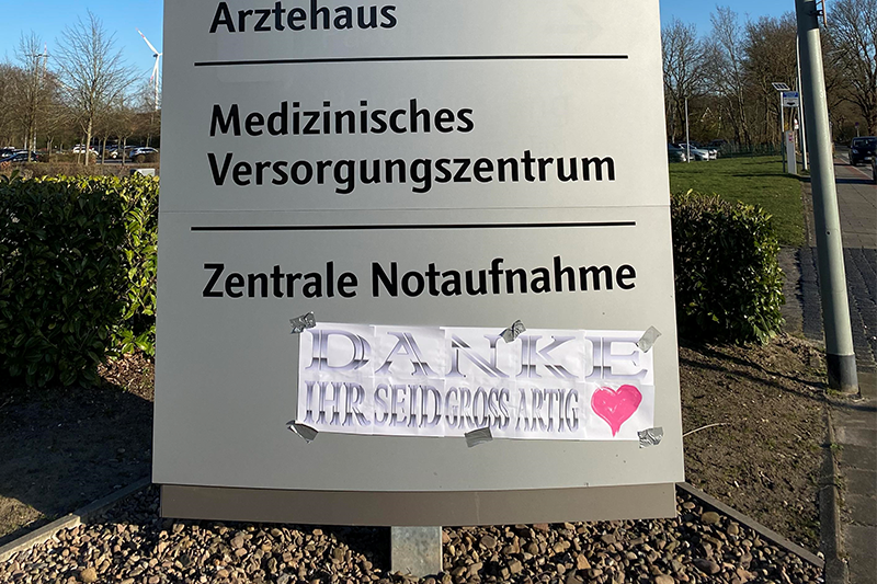 Der Orientierungswegweiser an der Zufahrt vom Klinikum Bremerhaven-Reinkenheide, auf den Unbekannte unten ein Plakat geklebt haben mit der Aufschrift "Danke Ihr seid großartig" und einem pinkfarbenen Herz