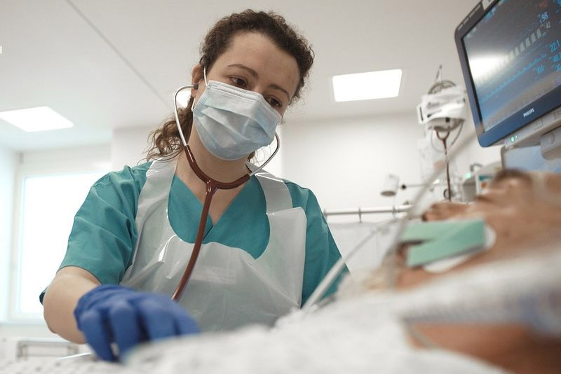 Schmuckbild: eine Pflegerin am Krankenbett eines beatmeten Patienten