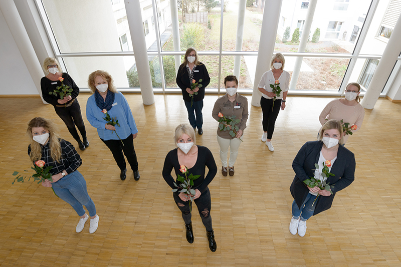 Gruppenfoto von neun frisch ausgebildeten Patientenassistentinnen am Klinikum Bremerhaven-Reinkenheide, jede hält eine gelb-rote Rose (Foto: Antje Schimanke)