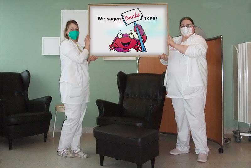 Zwei Pflegefachkräfte der Station 4A im neugestalteten Stillzimmer halten ein Schild mit dem Spendenmaskottchen Krabbi und dem Text "Wir sagen danke, IKEA!" (Foto: Wolber)