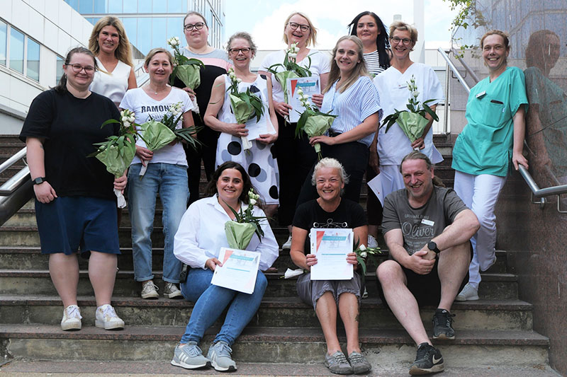 Die Absolventen und Absolventinnen des Pflegemanagement-Kurses 2023 auf der Treppe vor dem Haupteingang des Klinikums Bremerhaven-Reinkenheide.