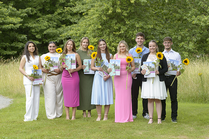 Neun Absolventen und Absolventinnen der Pflegeakademie mit ihren Berufsurkunden und einer Blume (Foto: Schimanke)