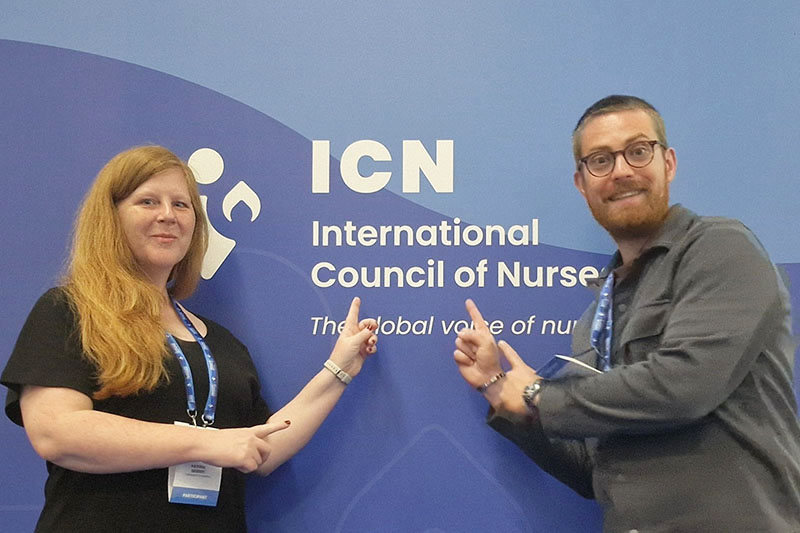 Dr. Kathrin Seibert und Julien Pöhner vor einer blauen Wand mit dem Schriftzug des ICN-Welzkongress 2025