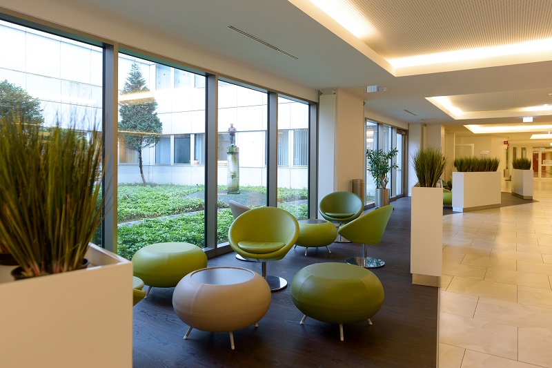 Eingangsbereich des Klinikums Bremerhaven-Reinkenheide mit Sesseln, Pflanzen und großen Fenstern; verlinkt zur Seite 'Ihr Aufenthalt'