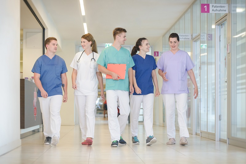 eine Gruppe von fünf jungen Pfegeauszubildenden geht nebeneinander auf einem Flur im Klinikum Bremerhaven-Reinkenheide