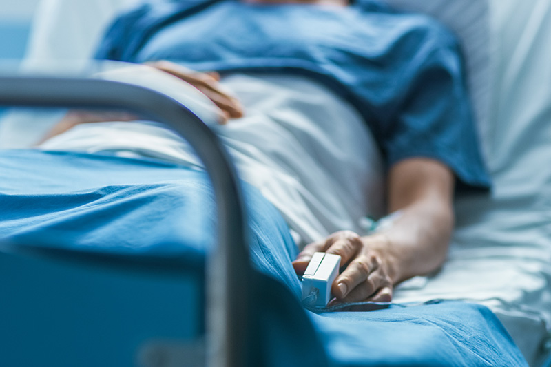Schmuckbild: Patient im Krankenhausbett mit Sauerstoffsensor am Finger (Quelle: Adobe Stock)