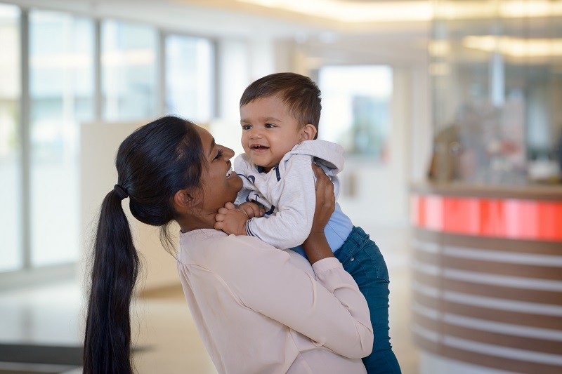 eine Mutter hebt ihren kleinen Sohn hoch, in der Eingangshalle des Klinikums Bremerhaven-Reinkenheide