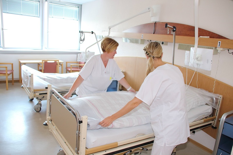 Zwei Krankenschwestern bereiten ein Krankenbett für den Transport und Umzug vor